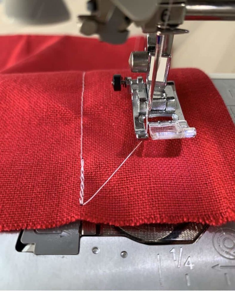 Three lines of stitches on a red piece of fabric