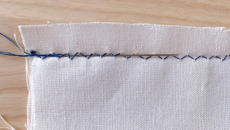 pulling the needle with a thread underneath the blind hem stitch 