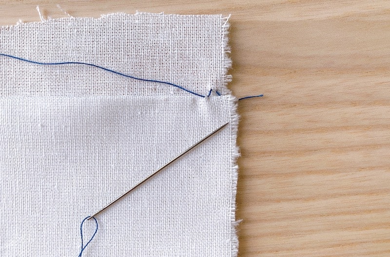 sewing blind hem stitch by hand on a white fabric