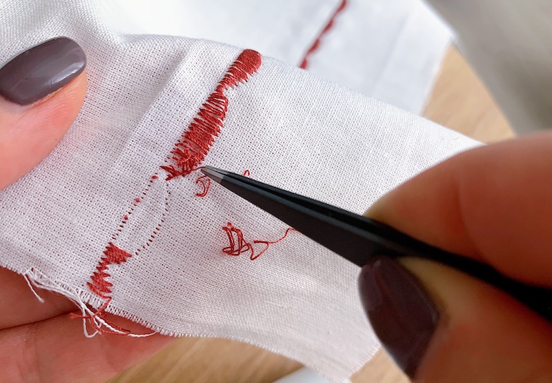 pulling out threads from embroidery stitch with tweezers