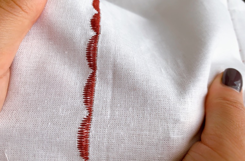 person holding a piece of white fabric with embroidery on it