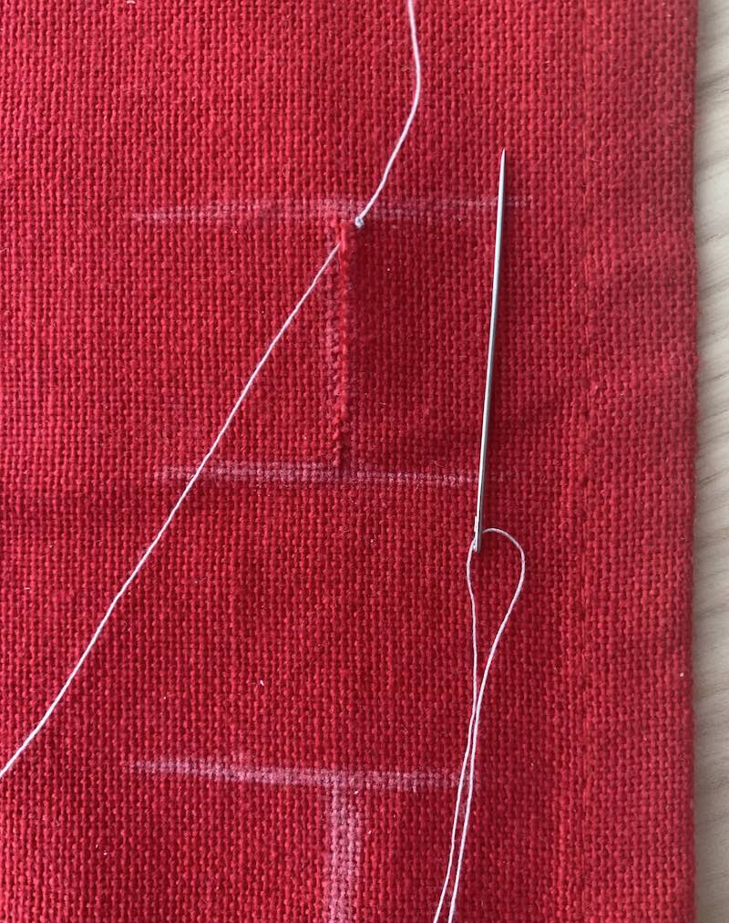 needle and thread pushed through the top of the fabric