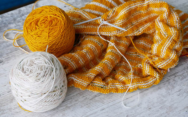 white and yellow yarn cakes on an unfinished knitting