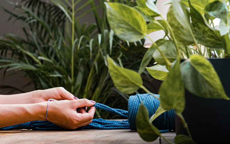 woman tying macrame with blue color rope